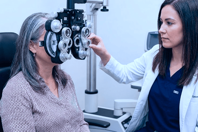 Ophthalmologist performing eye exam with phoropter on patient.