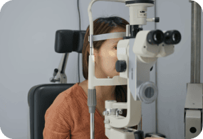 Woman undergoing eye exam using a slit lamp microscope at GRM Clinical.